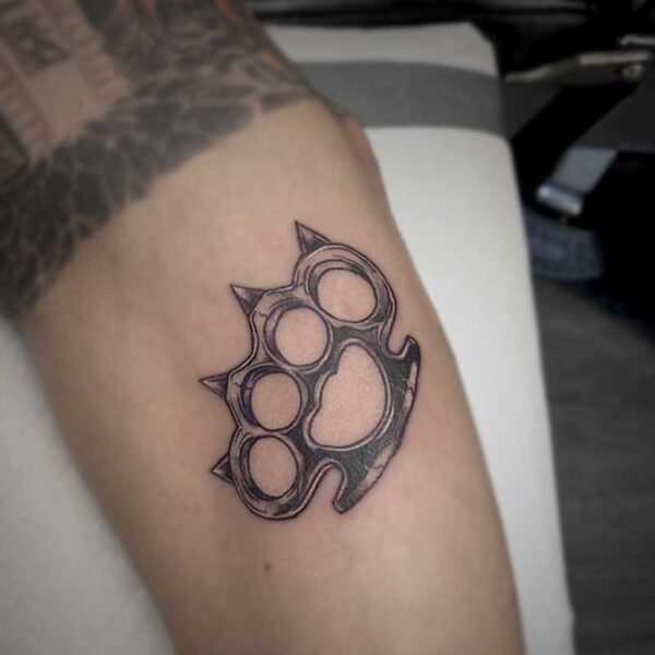 black and white tattoo of brass knuckles that are shaped like a cats paw