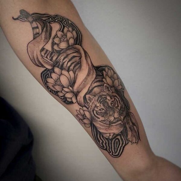 black and grey tattoo of a tiger with flowers and ribbon