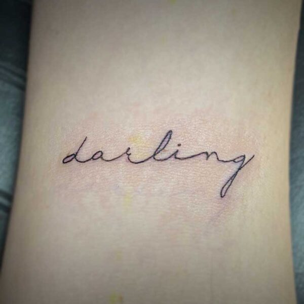 black and white script tattoo of the word darling