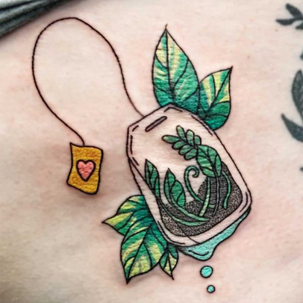 atticus tattoo, coloured tattoo of a tea bag with leaves and foliage in the centre