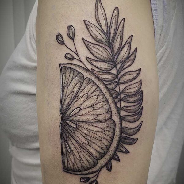 black and white tattoo of a lemon wedge and foliage
