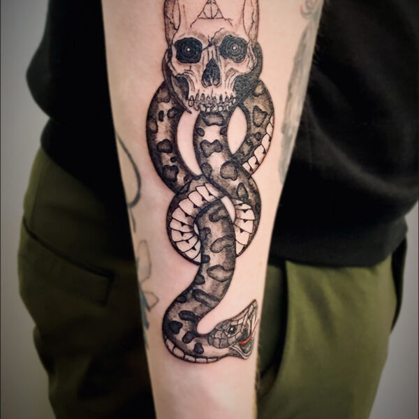 black and white tattoo of a human skull and a twisted snake