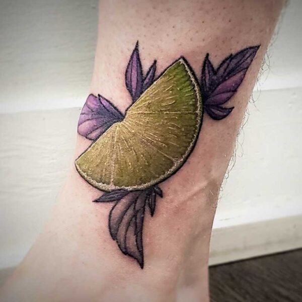 coloured tattoo of a lime wedge and purple leaves