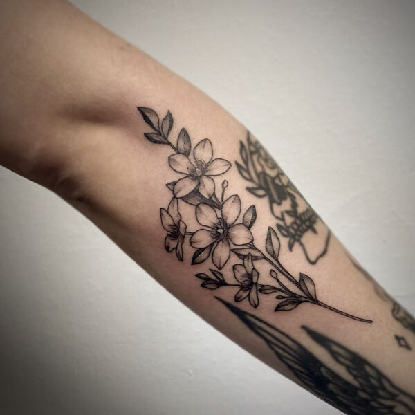 atticus tattoo, black and grey tattoo of a stem of flowers