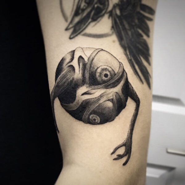 atticus tattoo, black and grey tattoo of a monster in the shape of a circle with arms and eyes