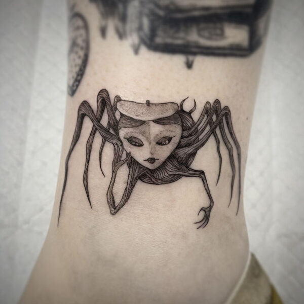 atticus tattoo, black and grey tattoo of a spider with a human face