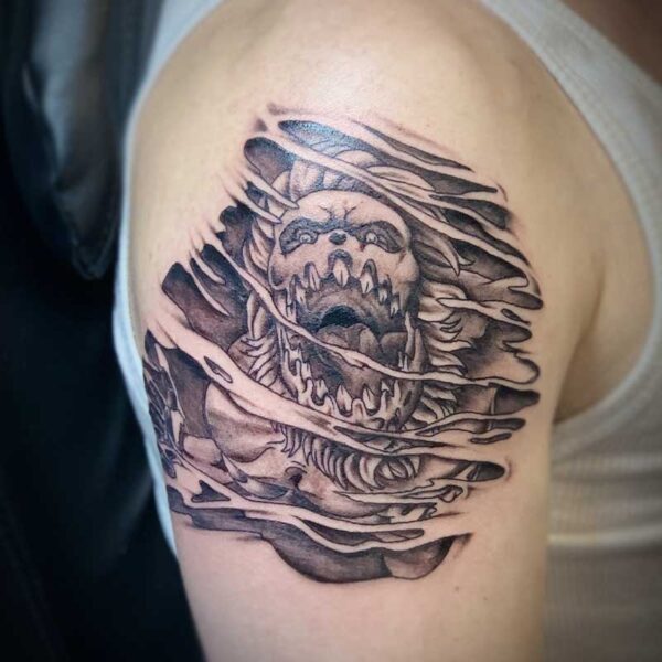 atticus tattoo, black and grey tattoo of a clown monster ripping through flesh