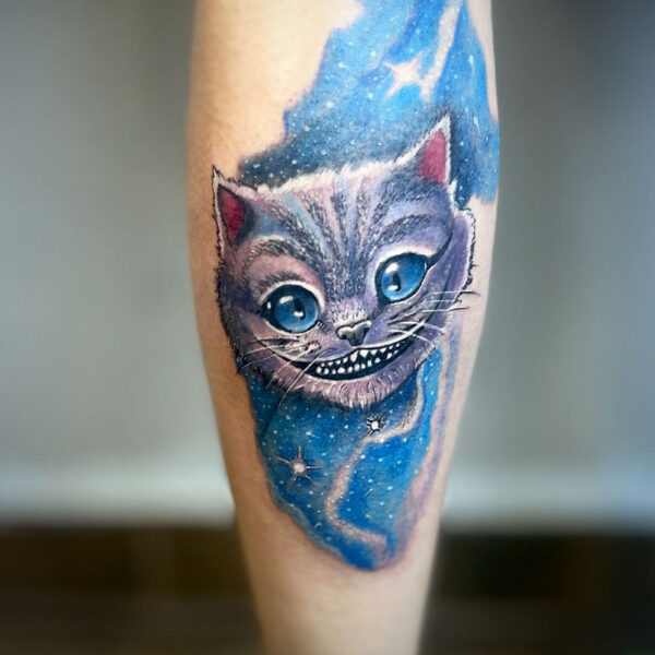 atticus tattoo, coloured tattoo of the Cheshire cat's head smiling and floating in space