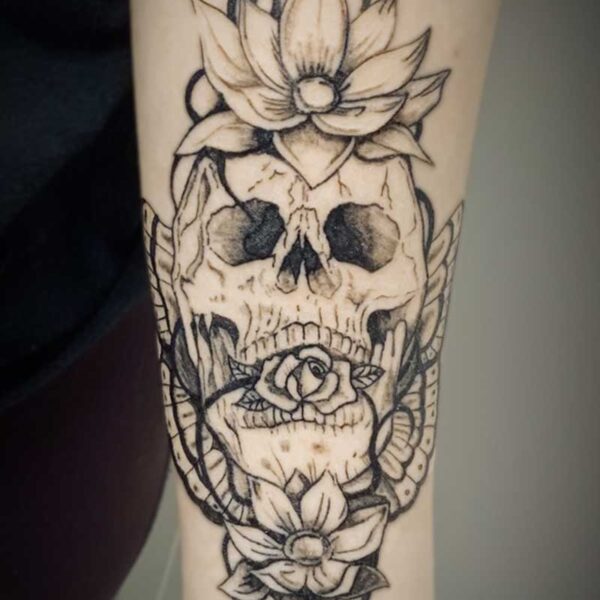 black and white tattoo of a human skull with flowers