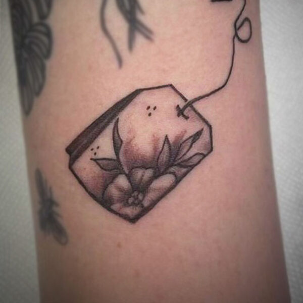 atticus tattoo, black and white tattoo of a tea back with flowers on it