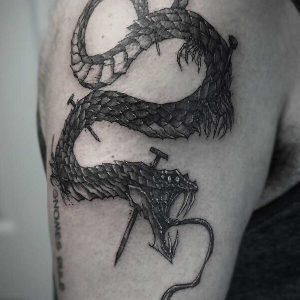 atticus tattoo, black and white tattoo of a monster snake with nails through its body