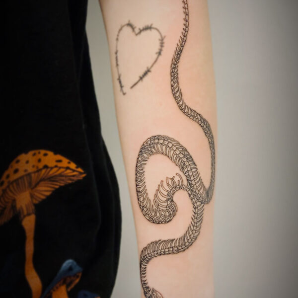 black and white tattoo of a snake skeleton