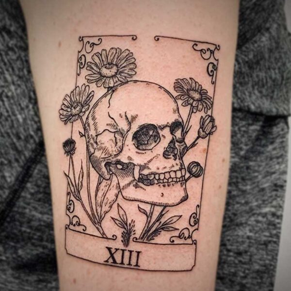 fine line tattoo of a tarot card with a human skull and daisies