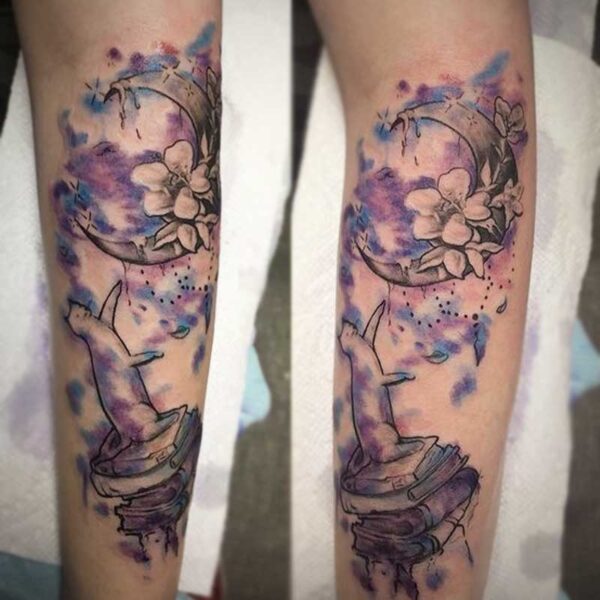 atticus tattoo, water colour tattoo of a cat sitting on books, reaching towards the moon and flowers