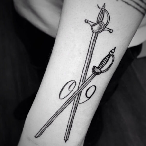 black and white tattoo of two swords crossing each other