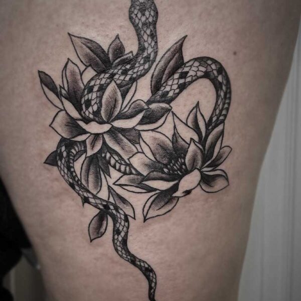 black and white tattoo of a snake and lotus flowers