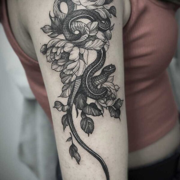 atticus tattoo, black and grey tattoo of a garter snake amongst flowers