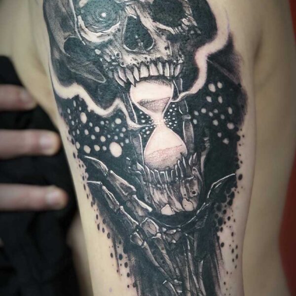 atticus tattoo, black and grey tattoo of a skeleton holding an hourglass in its mouth