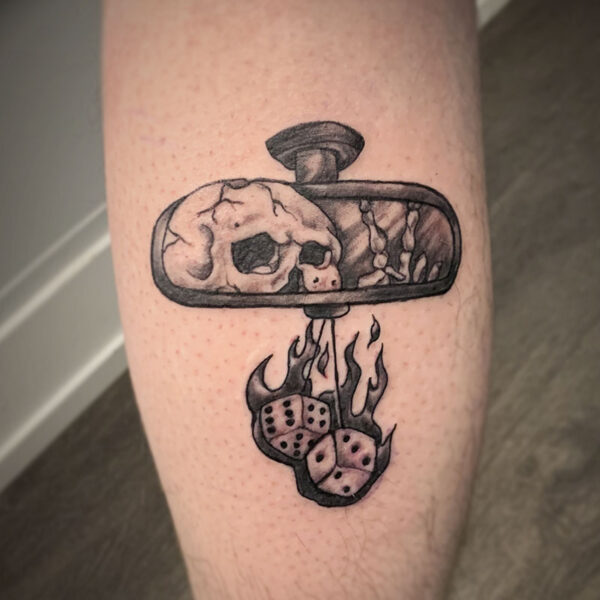atticus tattoo, black and grey tattoo of a skeleton looking in a rearview mirror with flaming dice hanging off of it