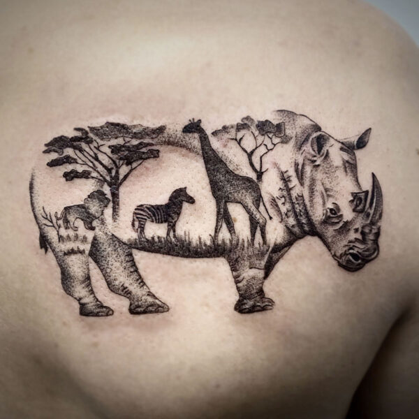 atticus tattoo, black and grey tattoo of a rhino with a safari scene as its body