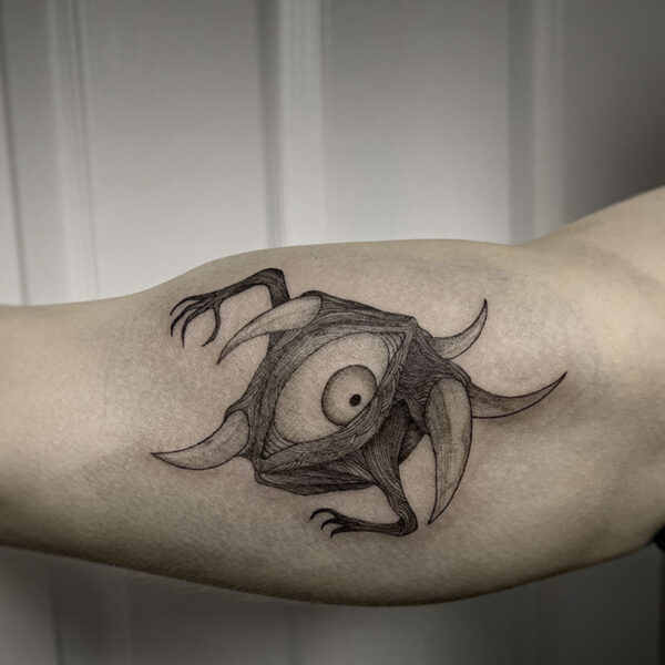 atticus tattoo, black and grey tattoo of a monster with one eye and spikes coming out of its head
