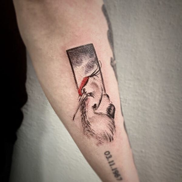 atticus tattoo, black and grey tattoo of a crane with a red head and a rectangle behind it