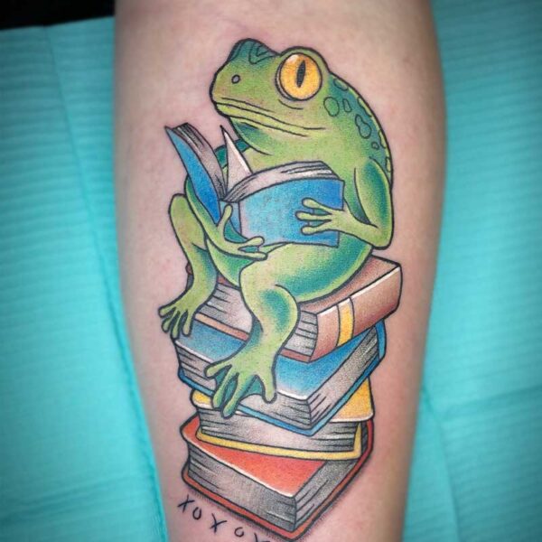 atticus tattoo, coloured neotraditional tattoo of a frog reading and sitting on a pile of books