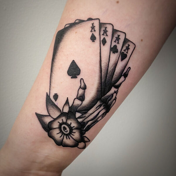 atticus tattoo, black and grey american traditional style tattoo of a skeleton hand holding a deck of aces