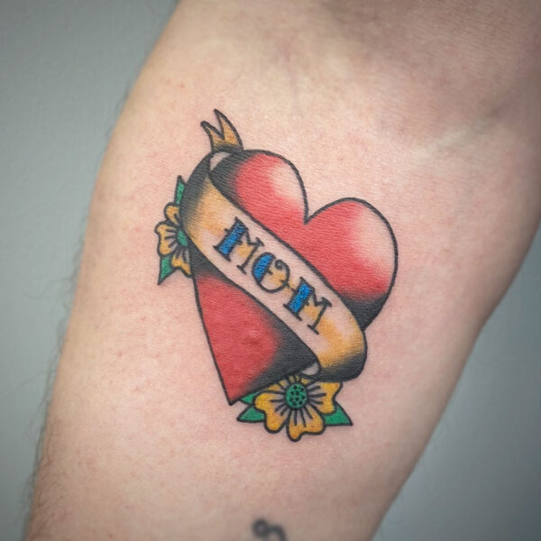 atticus tattoo, old school, coloured tattoo of a heart with flowers and a ribbon that says mom