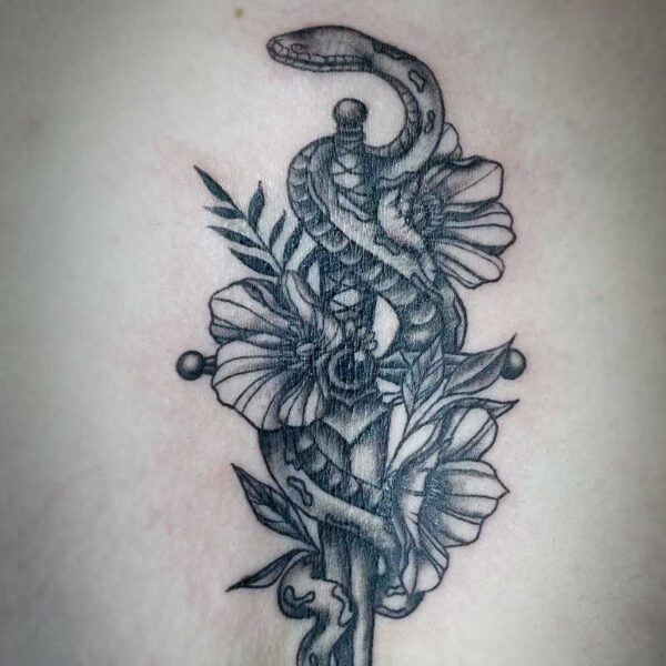 atticus tattoo, black and grey tattoo of a snake with a dagger and flowers