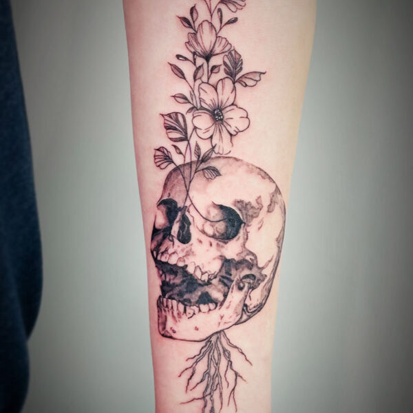 atticus tattoo, fine line tattoo of a skull with stemmed flowers behind it