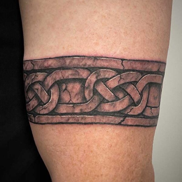 atticus tattoo, black and grey tattoo of an armband that looks like stone with celtic knots