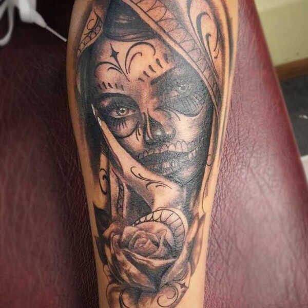 atticus tattoo, black and grey realism tattoo of a woman with a sugar skull mask and roses