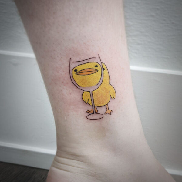 atticus tattoo, coloured tattoo of a yellow duck looking through a wine glass