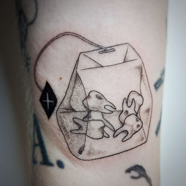atticus tattoo, black and white tattoo of a teabag with teeth in it