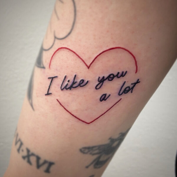 atticus tattoo, script tattoo of "I like you a lot" with a red outline of a heart