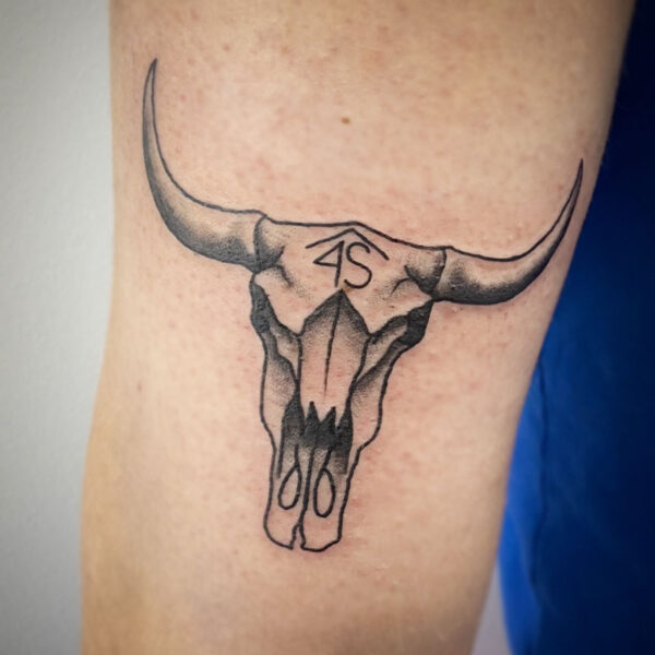 atticus tattoo, black and grey tattoo of a bull skull with a brand on its forehead