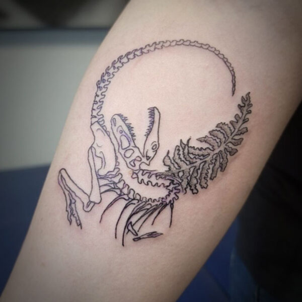 atticus tattoo, black and grey tattoo of a t-rex skeleton and a fern leaf