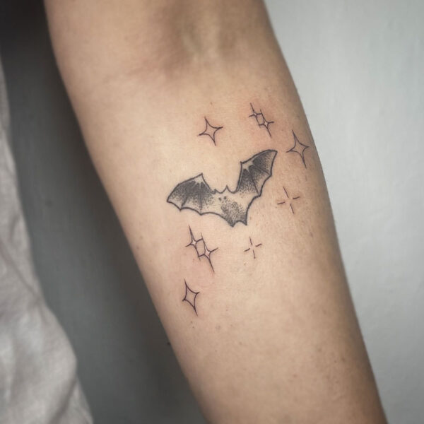 atticus tattoo, black and grey tattoo of a bat with sparkles