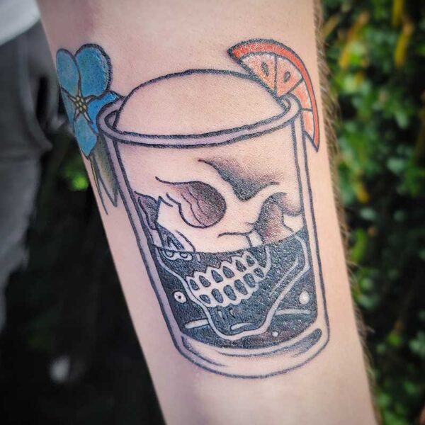 atticus tattoo, black and grey neotraditional tattoo of skull in a shot glass with a blue flower and an orange slice