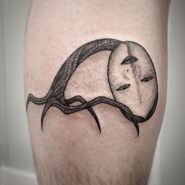 atticus tattoo, black and grey tattoo of a four legged creature with a human mask face