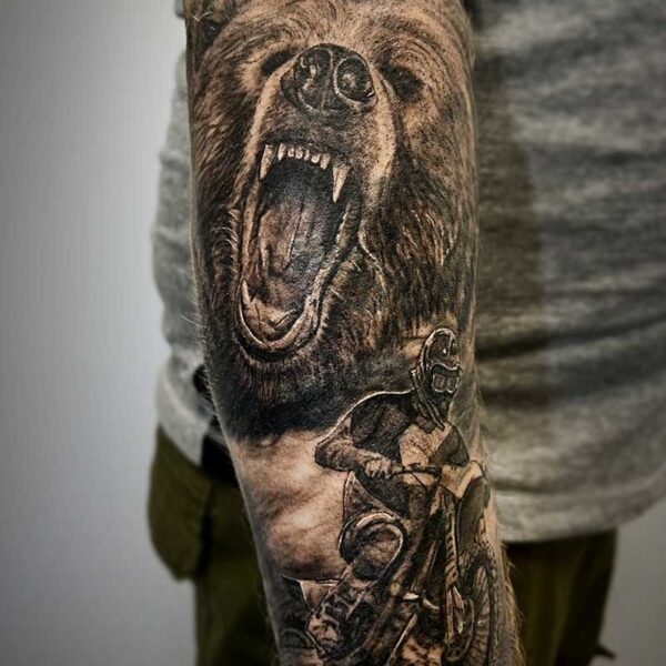atticus tattoo, black and grey realism tattoo of a grizzly bear roaring and a motocross biker