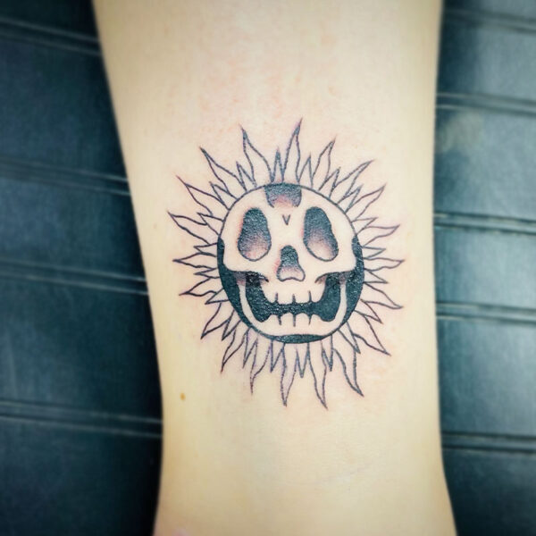 atticus tattoo, black and grey tattoo of the sun with a skull face
