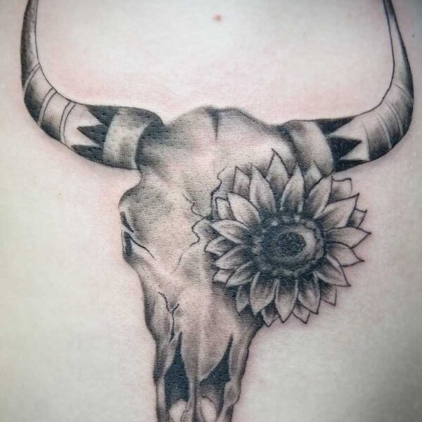 atticus tattoo, black and grey realism tattoo of a cow skull with a sunflower