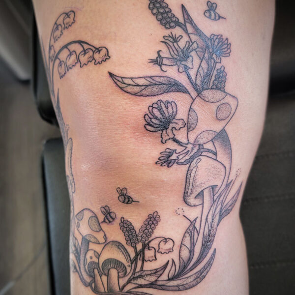 atticus tattoo, knee frame tattoo of mushrooms, flower and bees