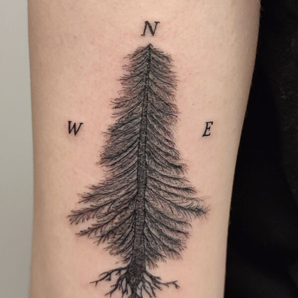 atticus tattoo; black and grey tattoo of a fir tree with N, S, E and W around it