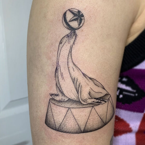 atticus tattoo, black and grey tattoo of a circus seal on a platform with a ball on its nose