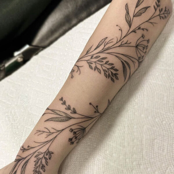 atticus tattoo; black and grey wrapped tattoo of a vine with flowers