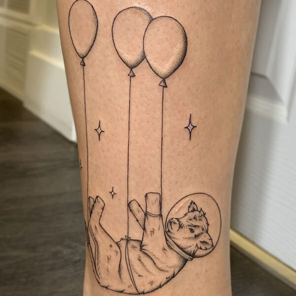 atticus tattoo, black and grey tattoo of a baby cow with an astronaut helmet floating with balloons