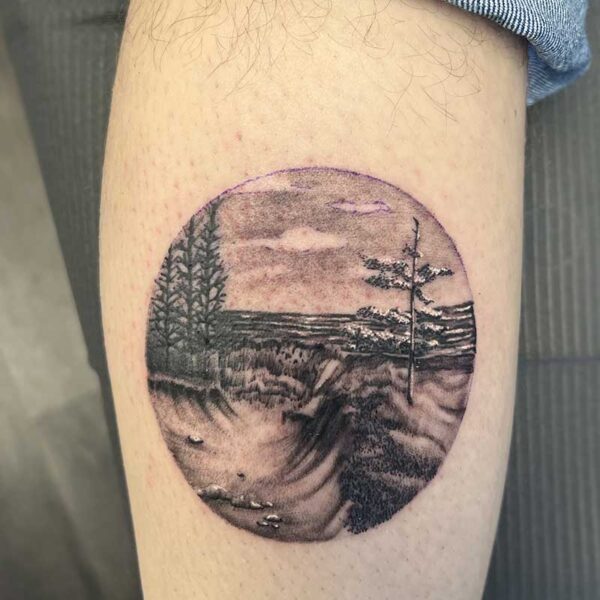 atticus tattoo, black and grey realism tattoo of a forest and lake scene, framed in a circle